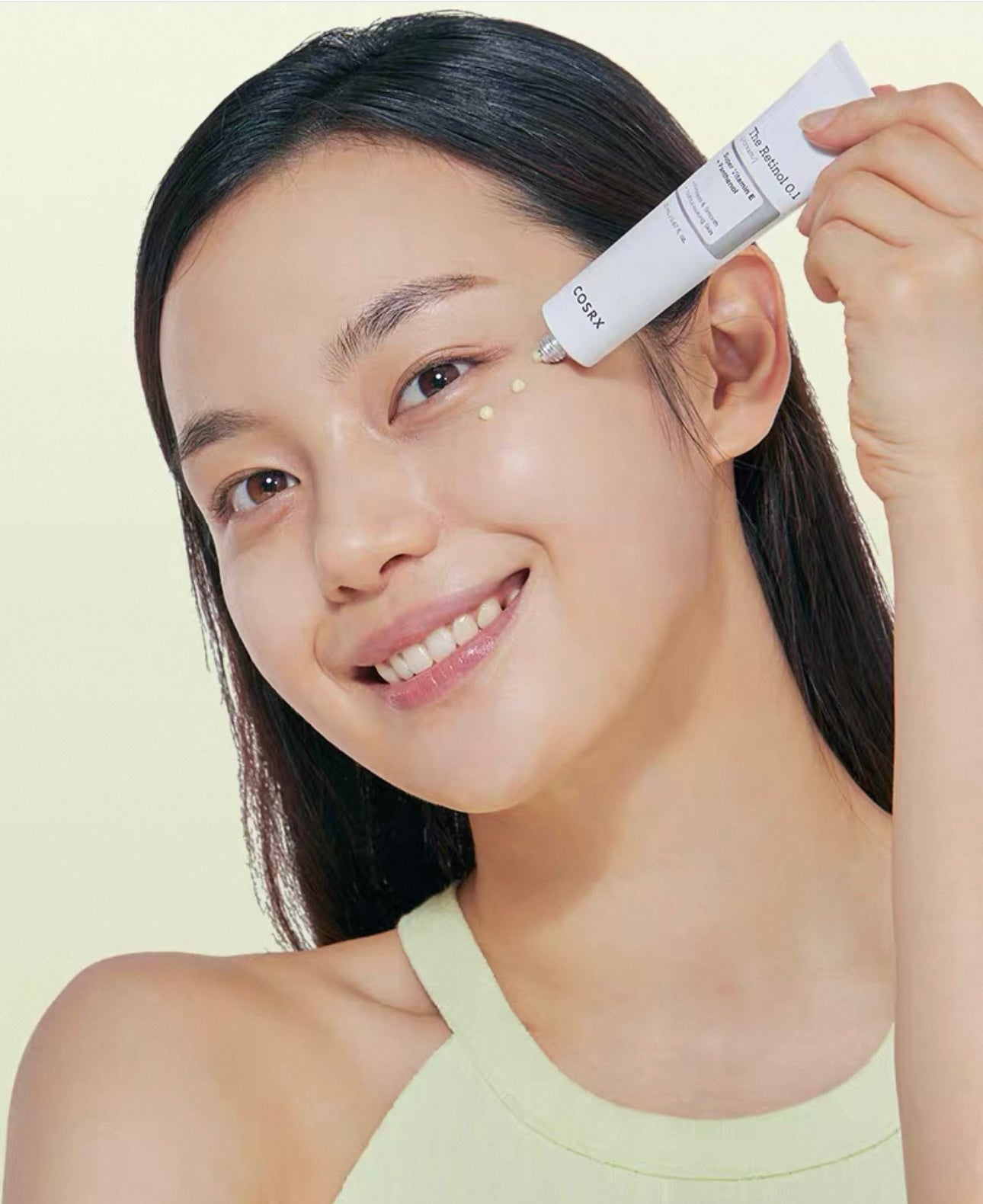 Woman applying COSRX The Retinol 0.1 Cream 20 ml to her face with a neutral background