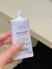Hand holding a white skincare product packaging with visible branding on a neutral background