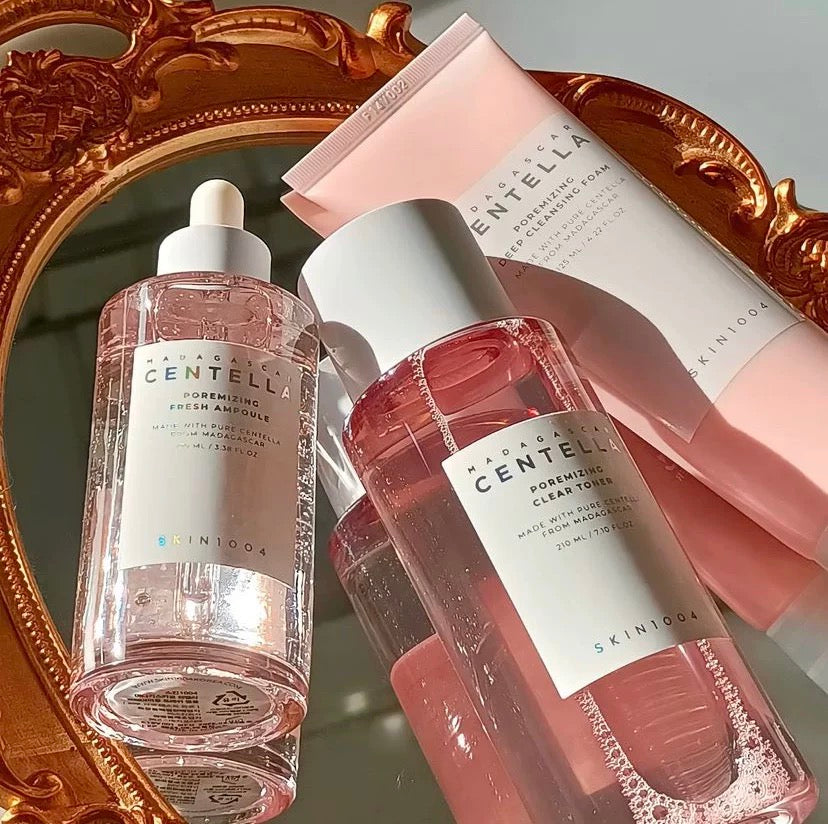 Two bottles of Centella SkinFood toner with a mirror and pink packaging in the background.