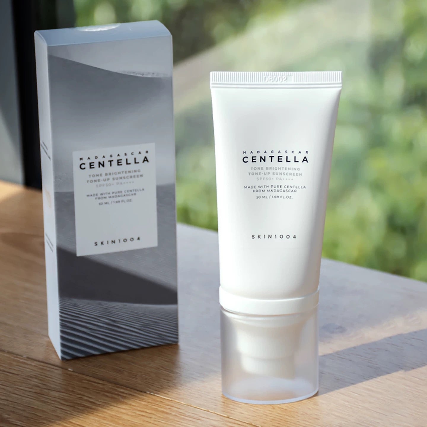Skintouch Madagascan Centella skincare product packaging on a wooden surface with a blurred natural background