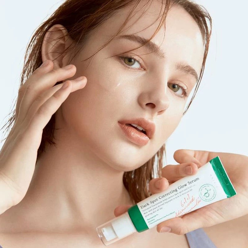 Woman holding a AXIS-Y Dark Spot Correcting Glow Serum 50ml with a plain background