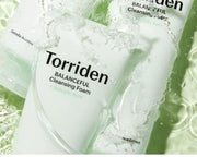 Torriden Balanceful Cleansing Foam packaging with water droplets on a green background